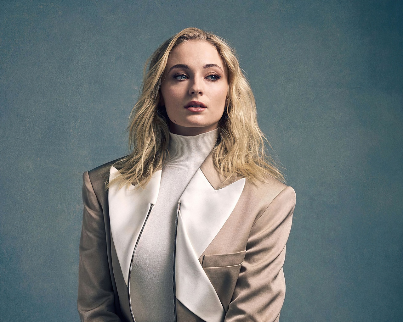 Актриса Софи Тёрнер в бежевом костюме на сером фоне