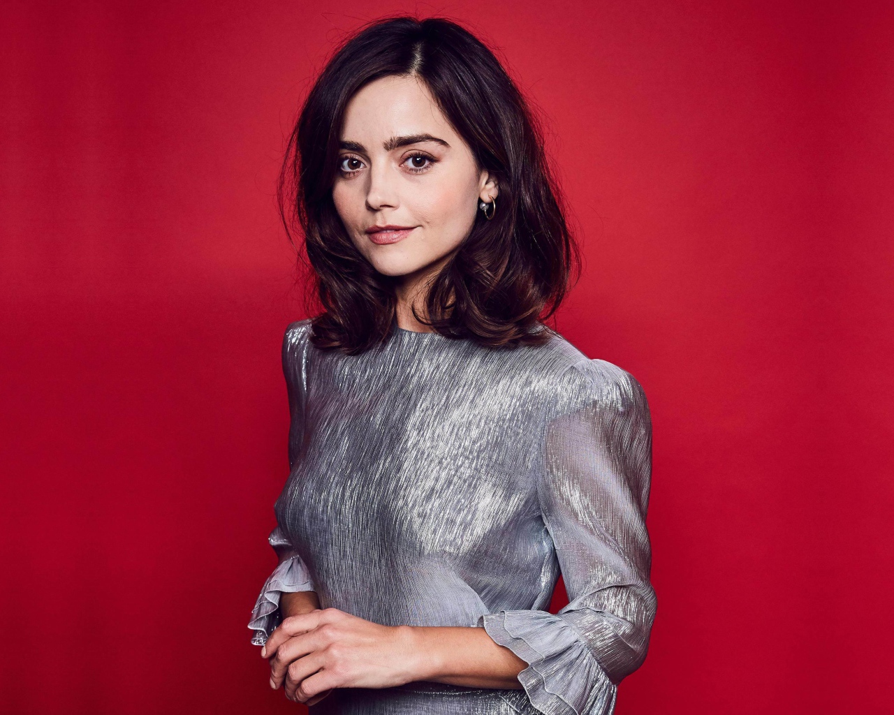 Американская актриса Дженна Коулман в сером платье на красном фоне