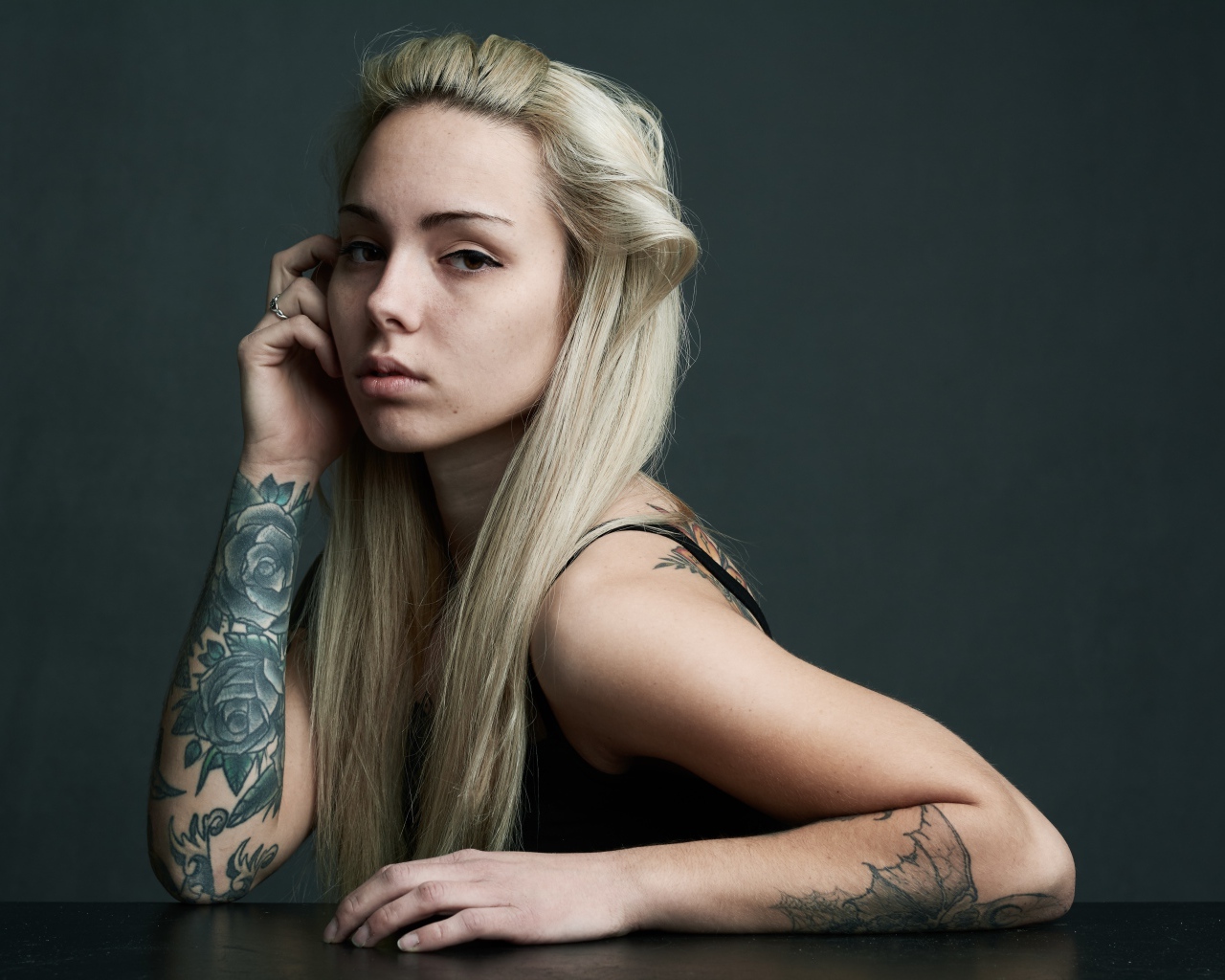 Beautiful blonde with tattoos on her body on a gray background