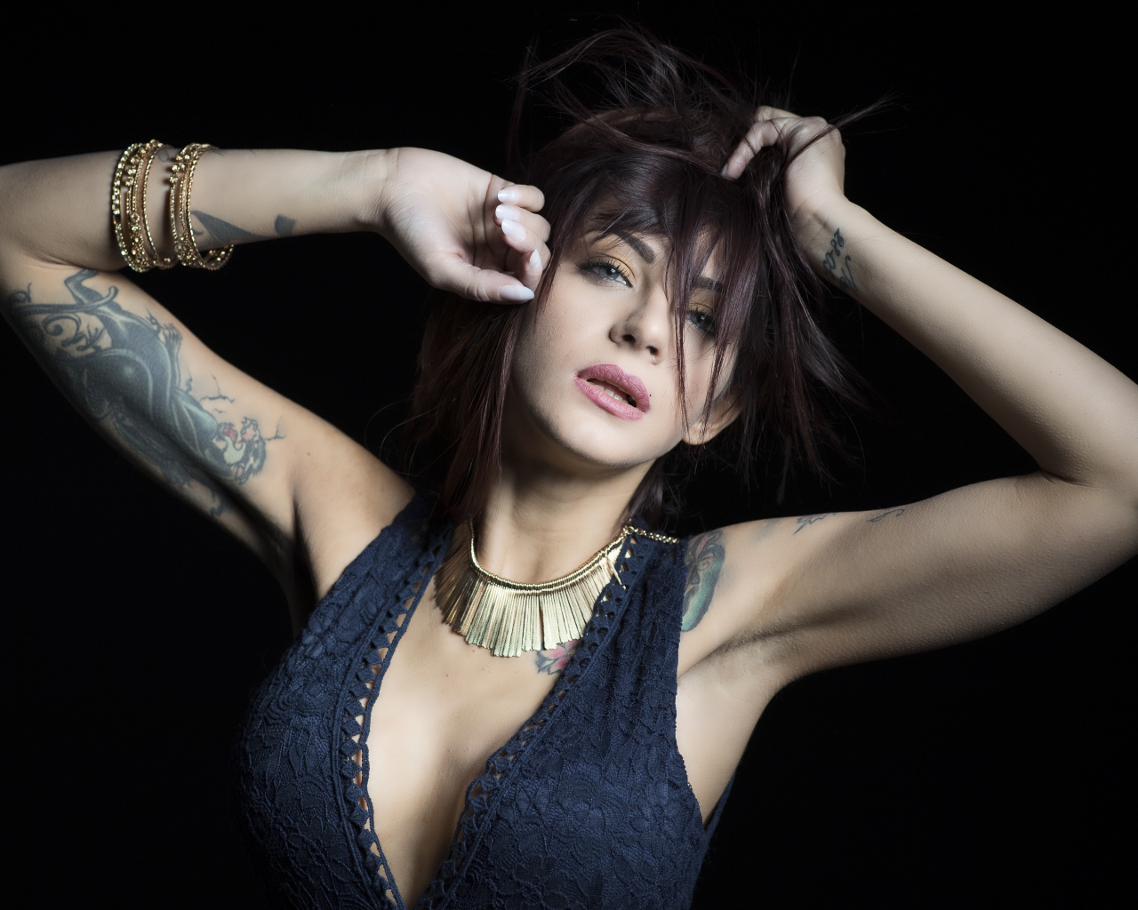 Красивая девушка в черном платье с татуировками на теле 