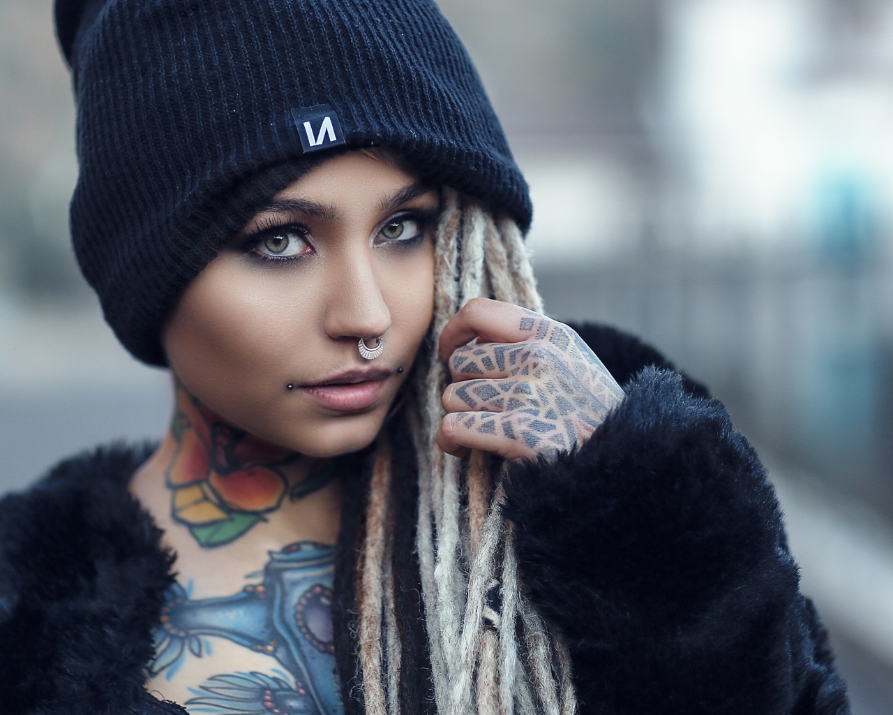 Красивая девушка в черной шапке с татуировками на теле 