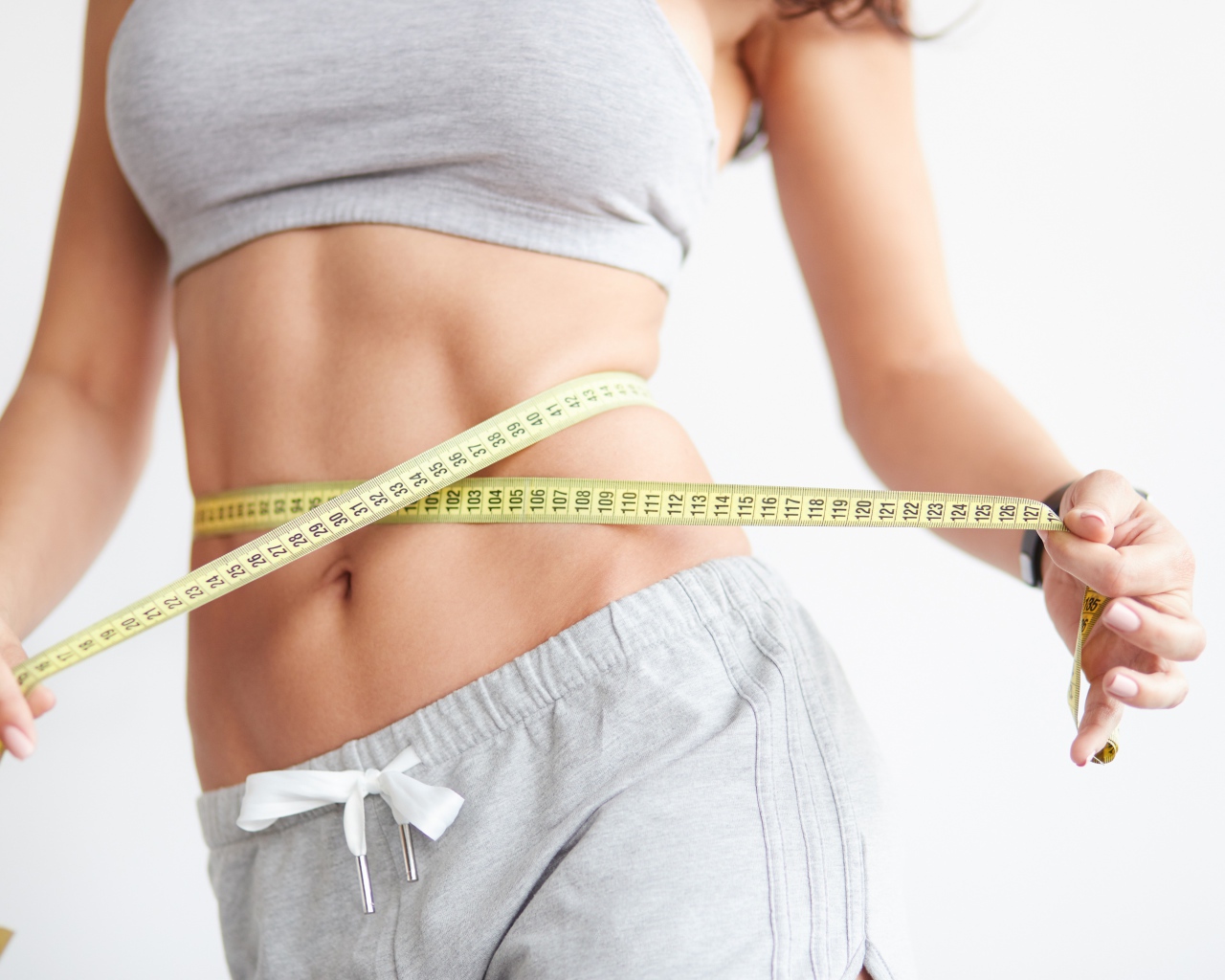 Красивая стройная девушка меряет талию сантиметром 