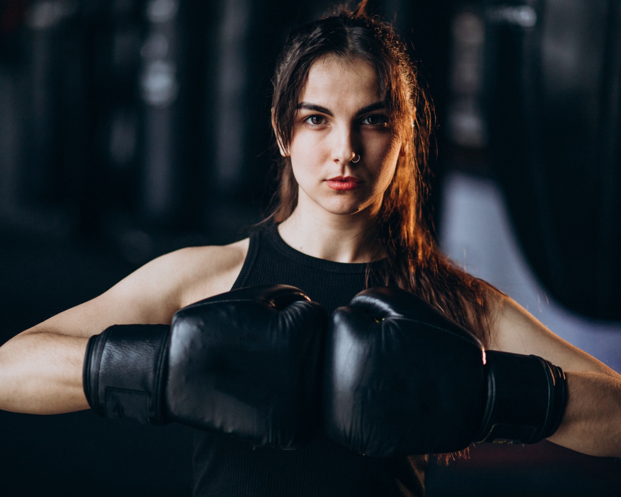 Девушка боксер с черными перчатками на руках 