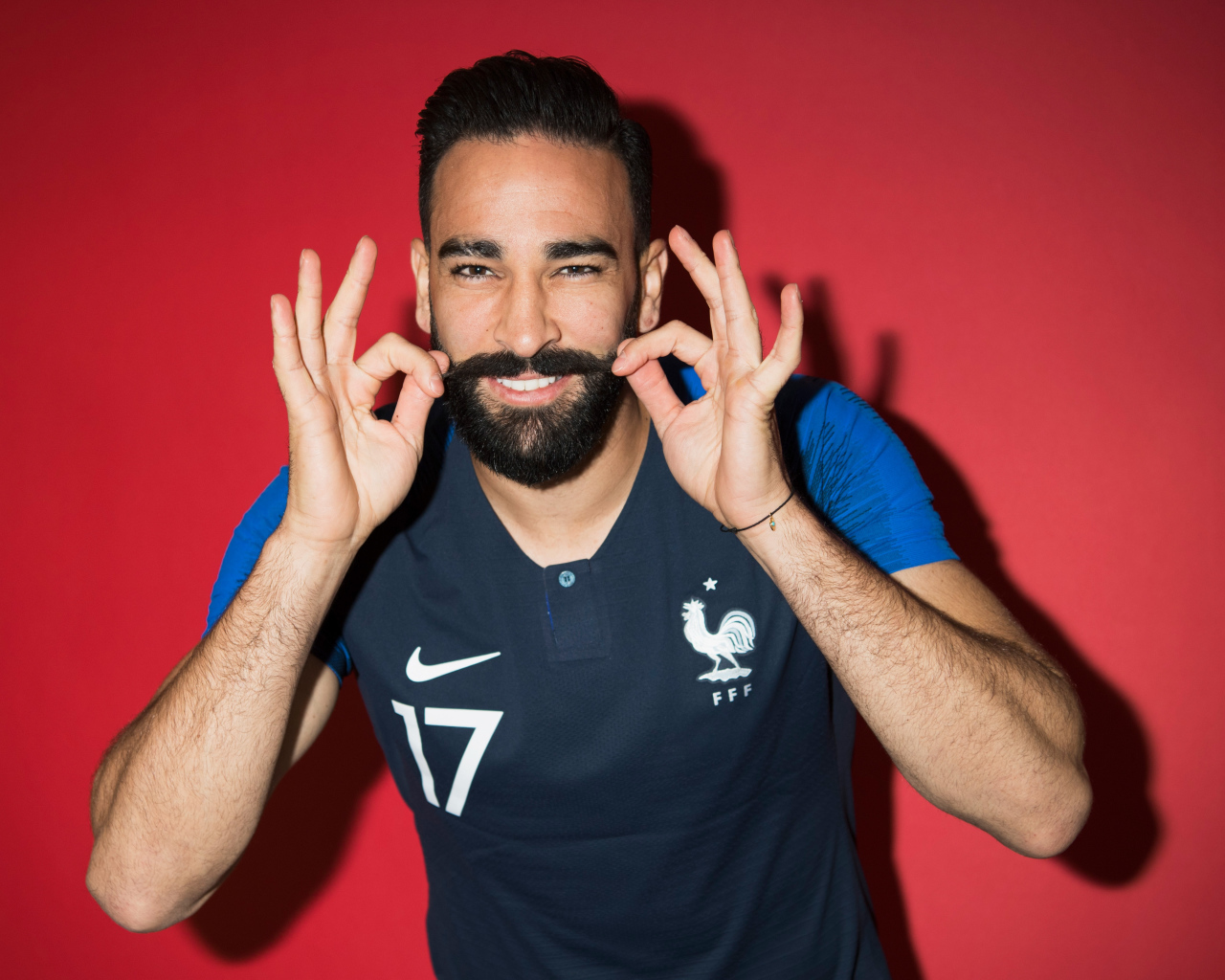 Французский футболист Адиль Рами на красном фоне