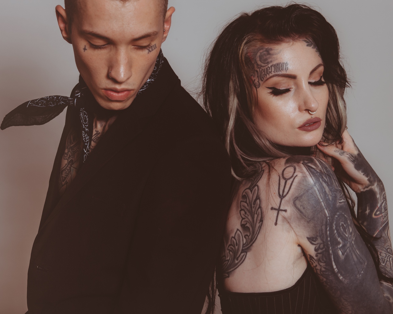 Girl and guy with tattoos on their bodies on a gray background