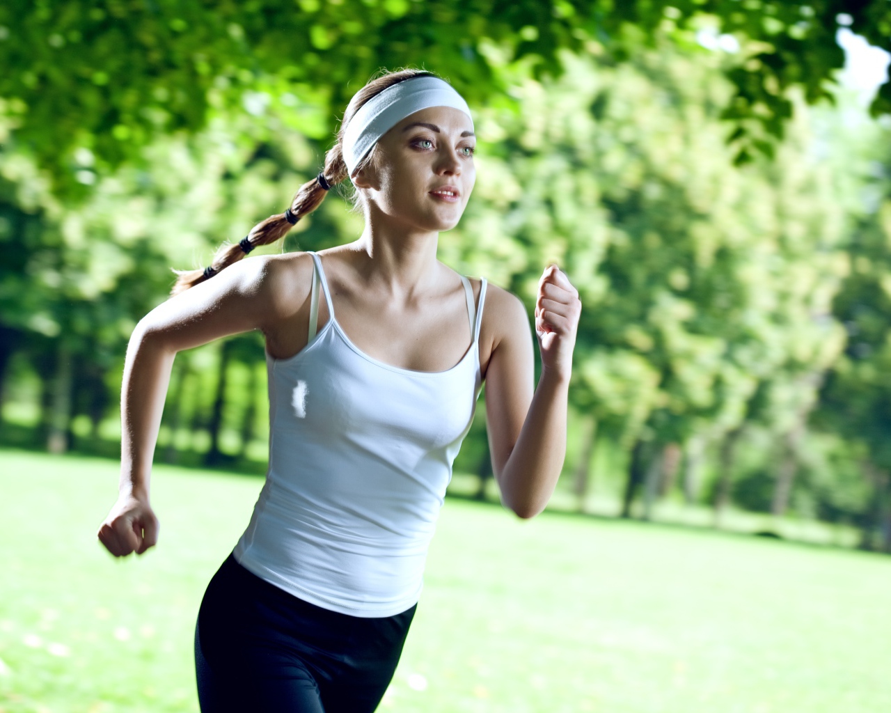 Девушка спортсменка в белой майке занимается бегом