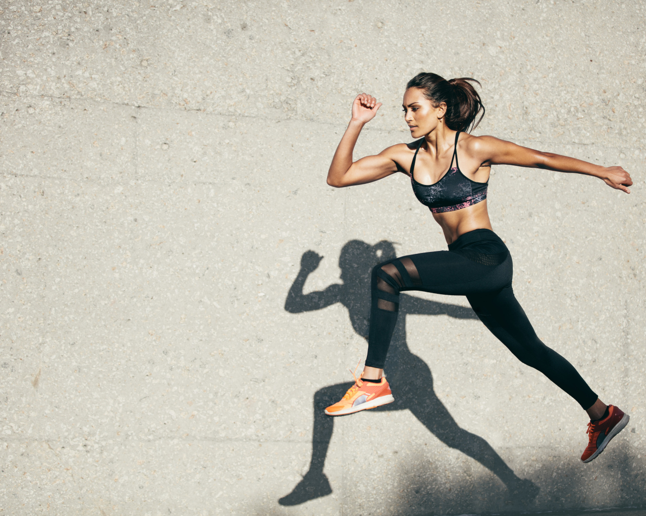 Девушка спортсменка бежит на стадионе 