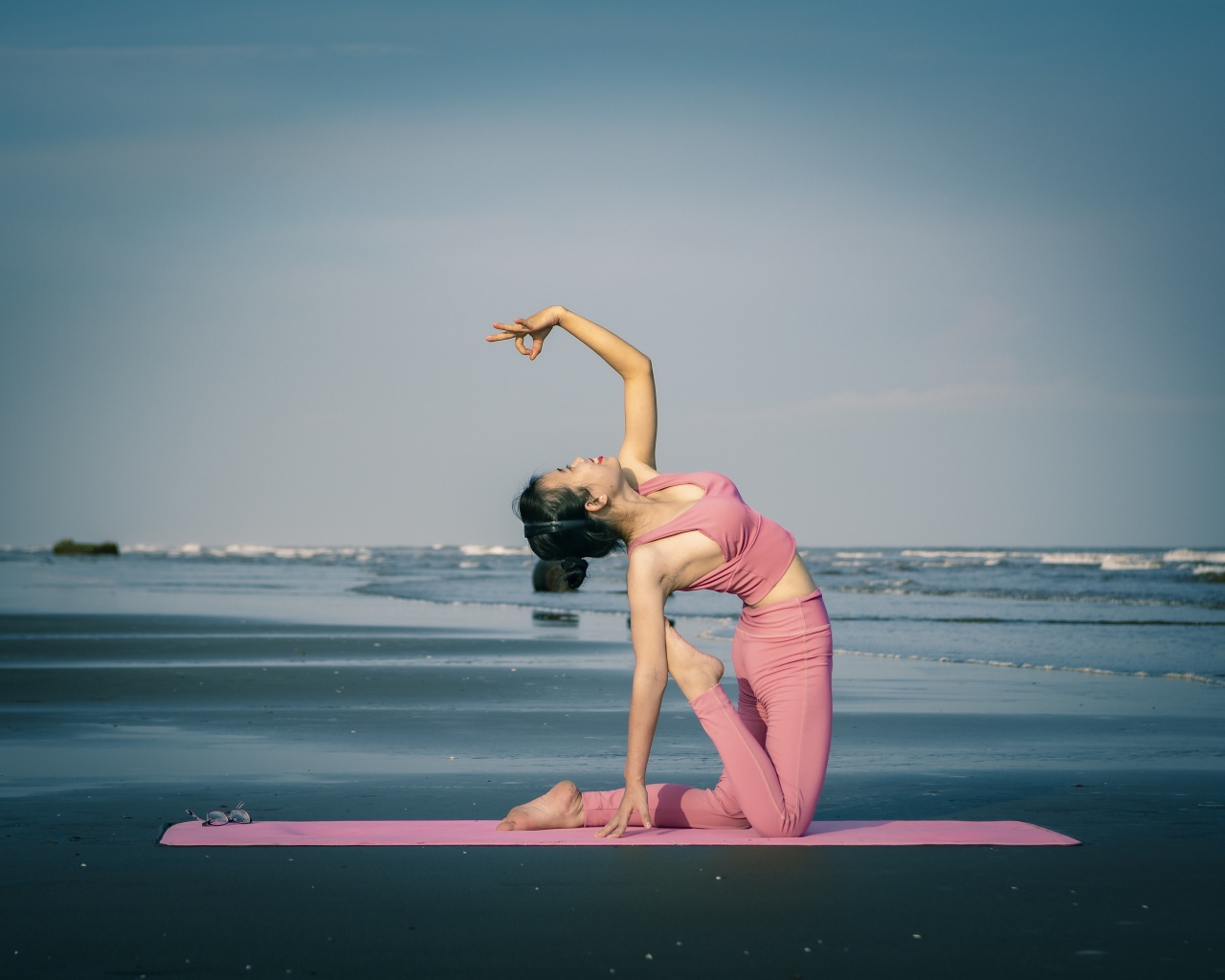 Девушка занимается йогой у моря 