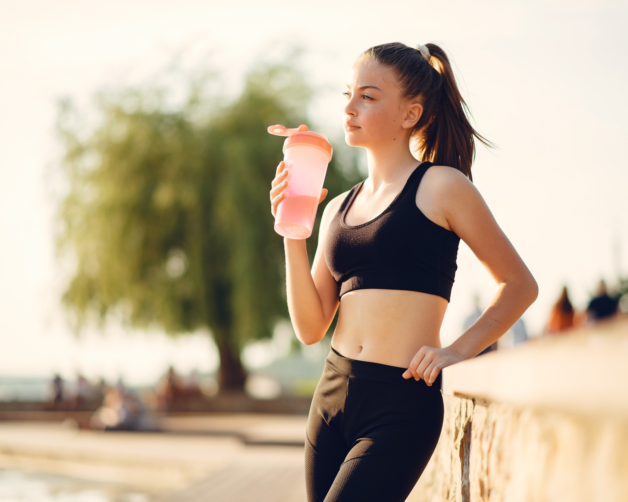 Девушка в черном спортивной форме с водой 