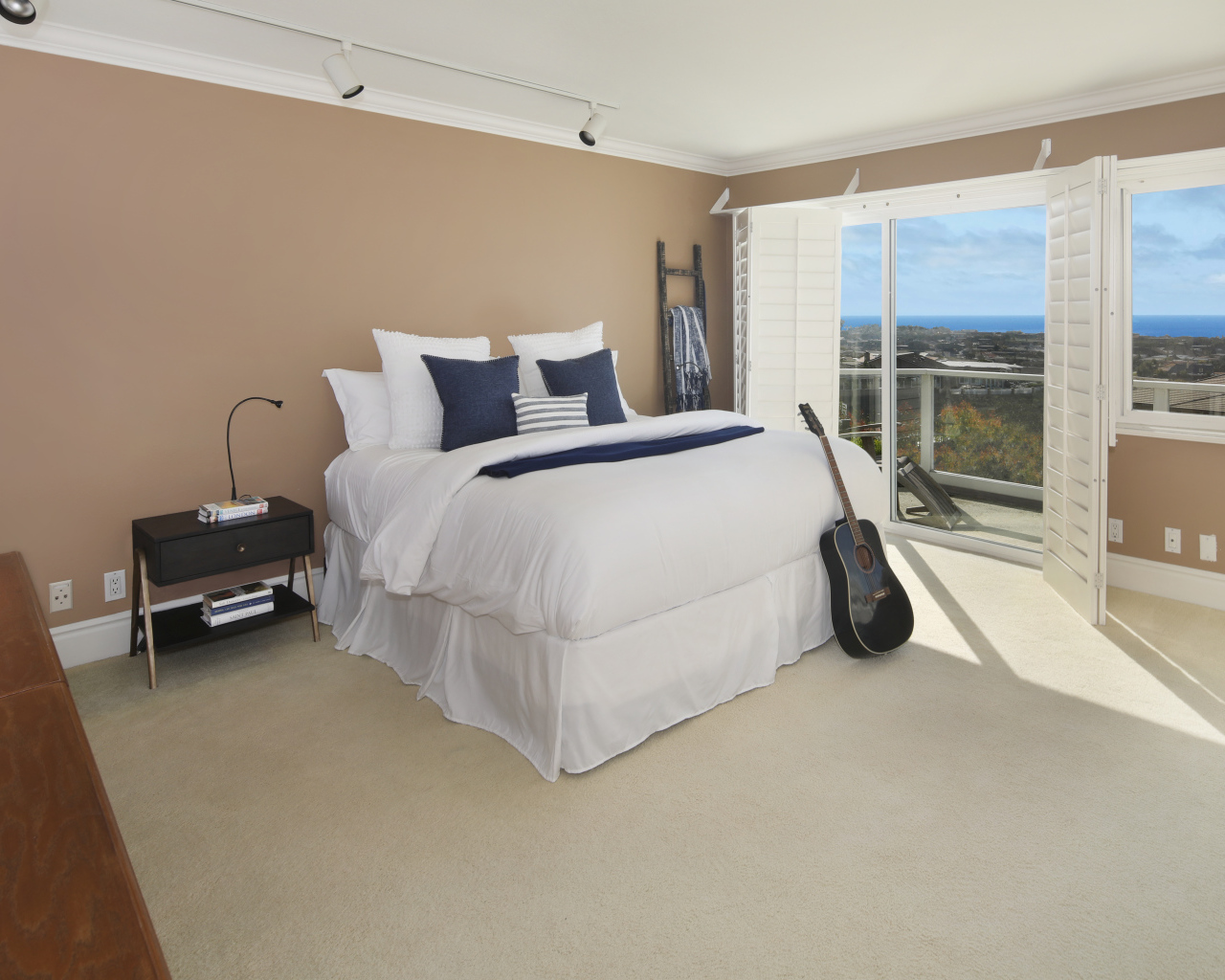 Большая высокая кровать в просторной спальне с гитарой 