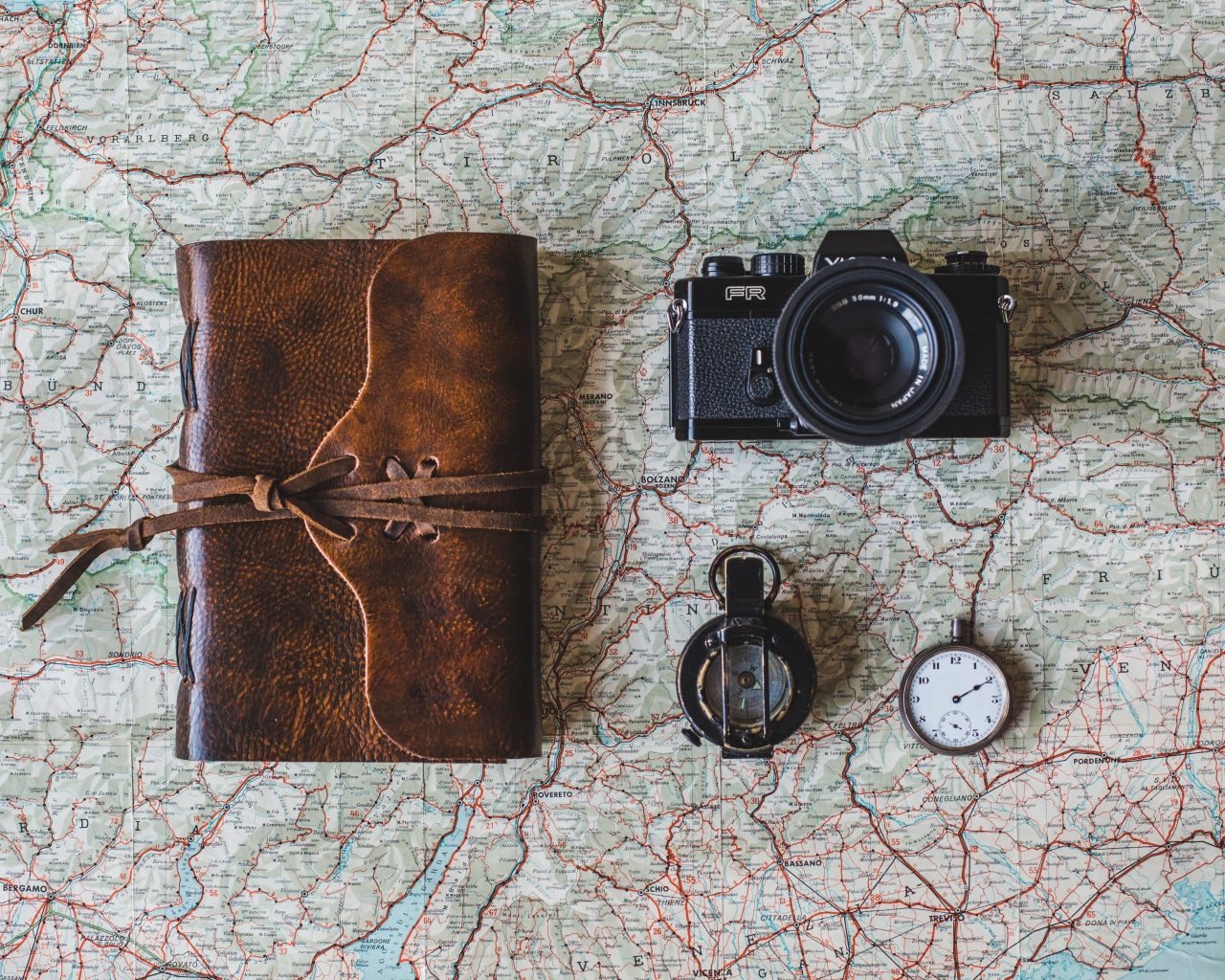 Старый фотоаппарат, компас, часы, блокнот и карта на столе