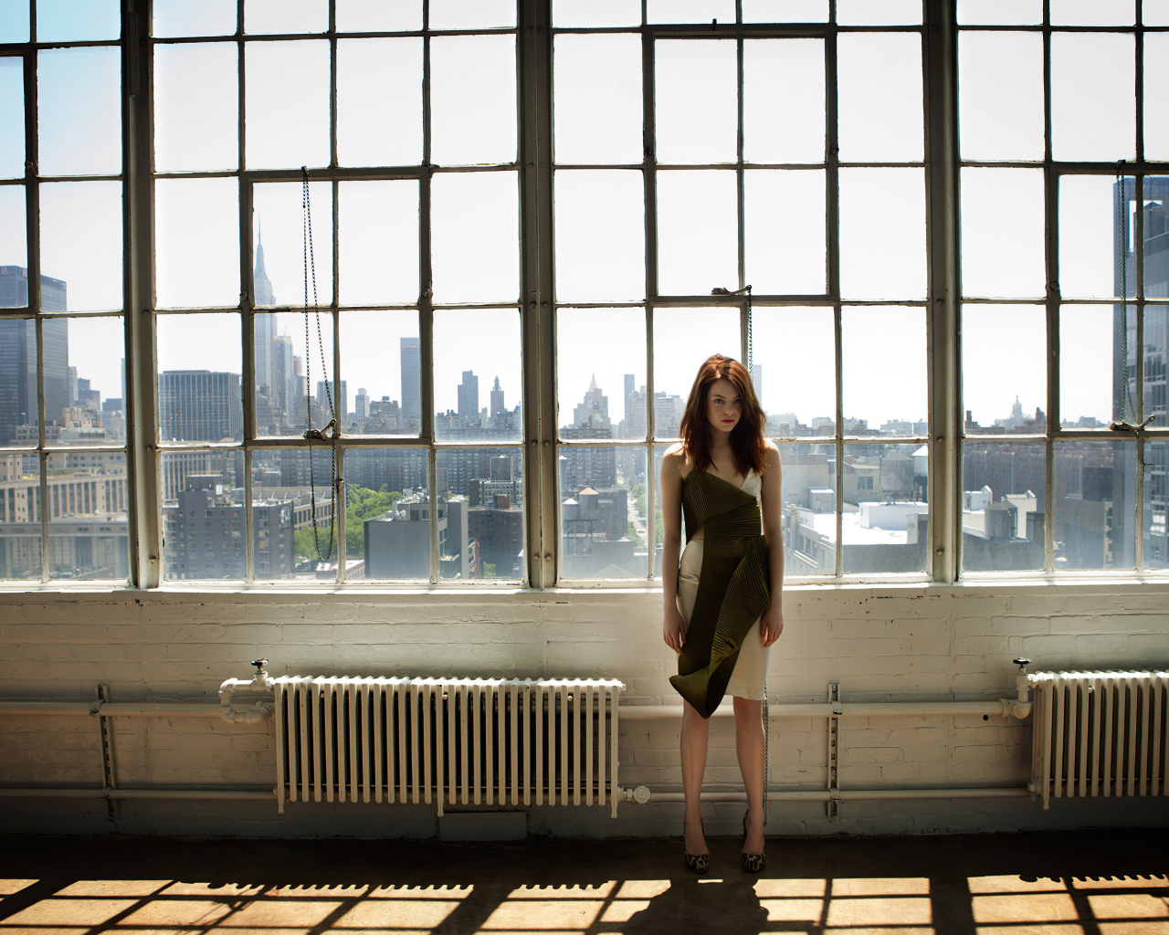 Популярная актриса Эмма Стоун стоит у большого окна