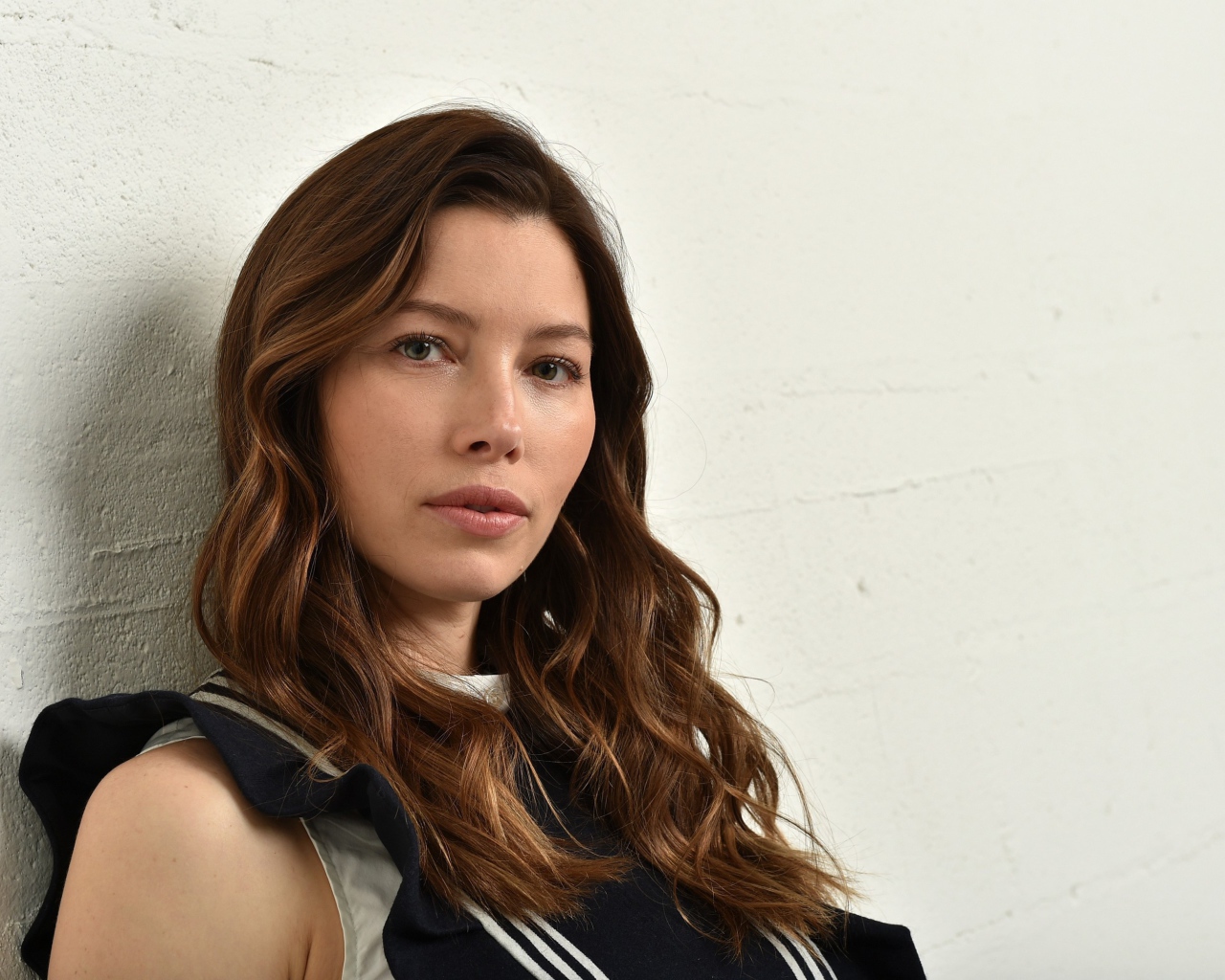 Грустная актриса Джессика Бил сидит у стены