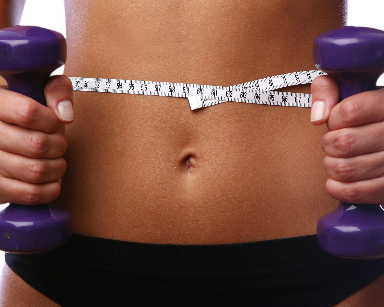 Стройная спортивная девушка с гантелями в руках 