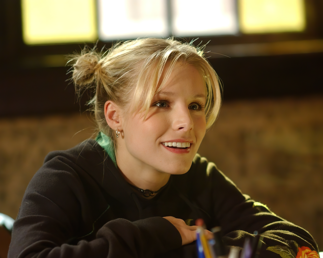 Улыбающаяся актриса Кристен Белл сидит в классе 