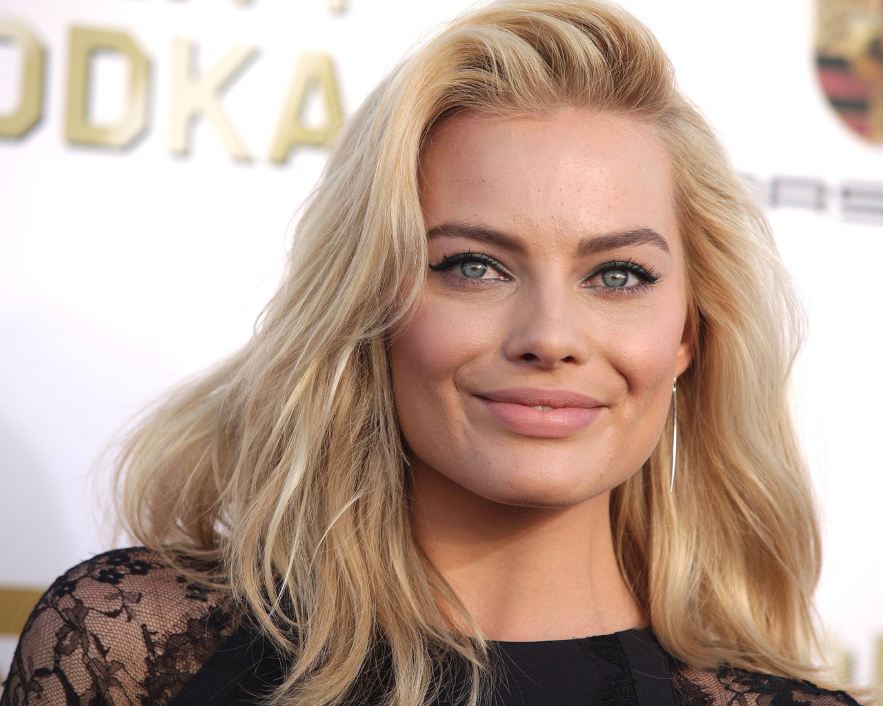 Улыбающаяся блондинка, актриса Марго Робби у стены