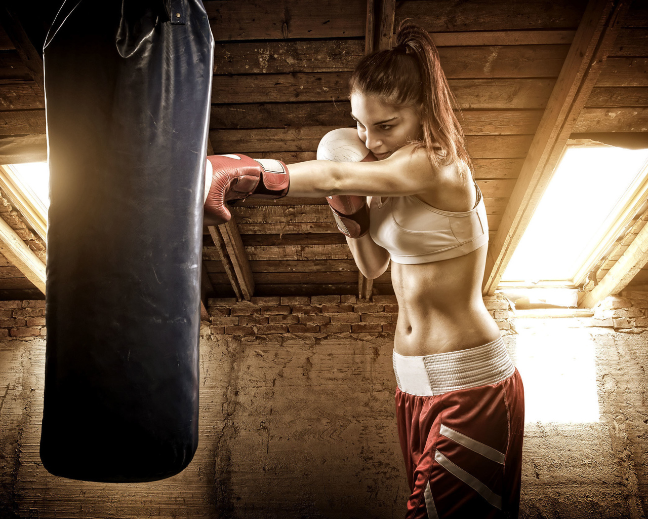Спортивная девушка бьет боксерскую грушу 