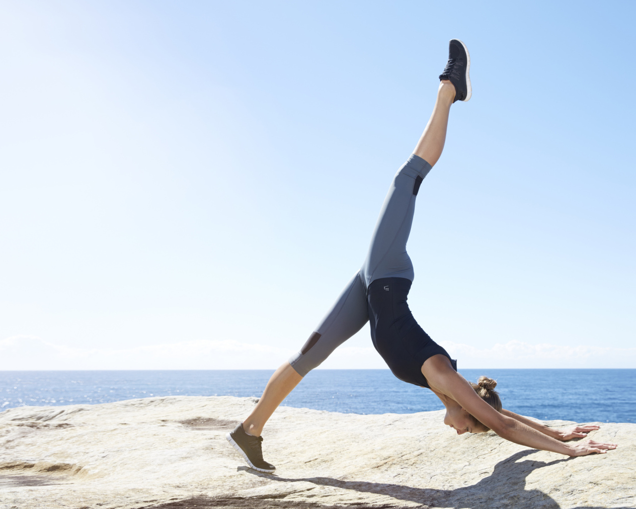 Спортивная девушка делает упражнения на берегу моря 