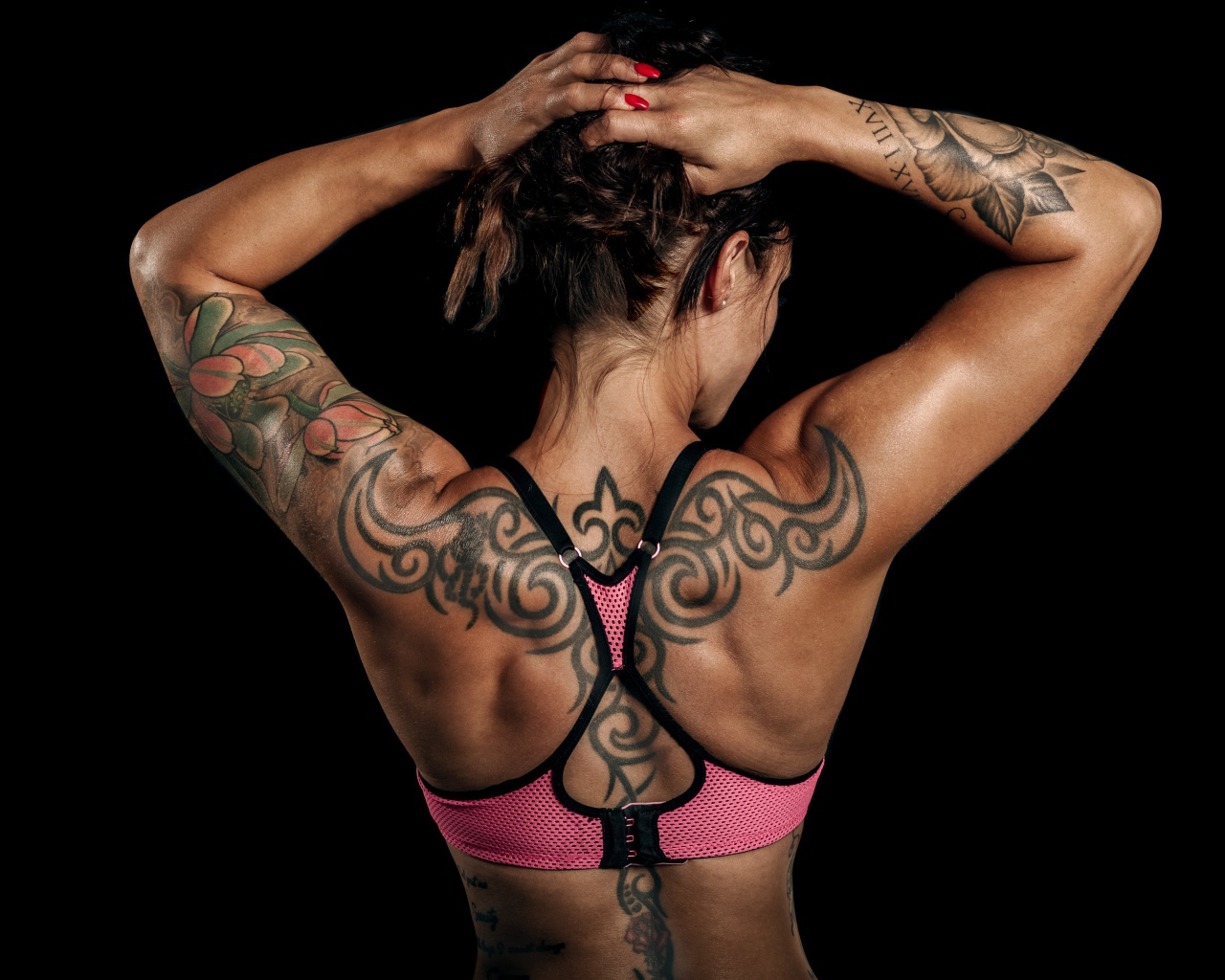 Татуировки на теле спортивной девушки на черном фоне