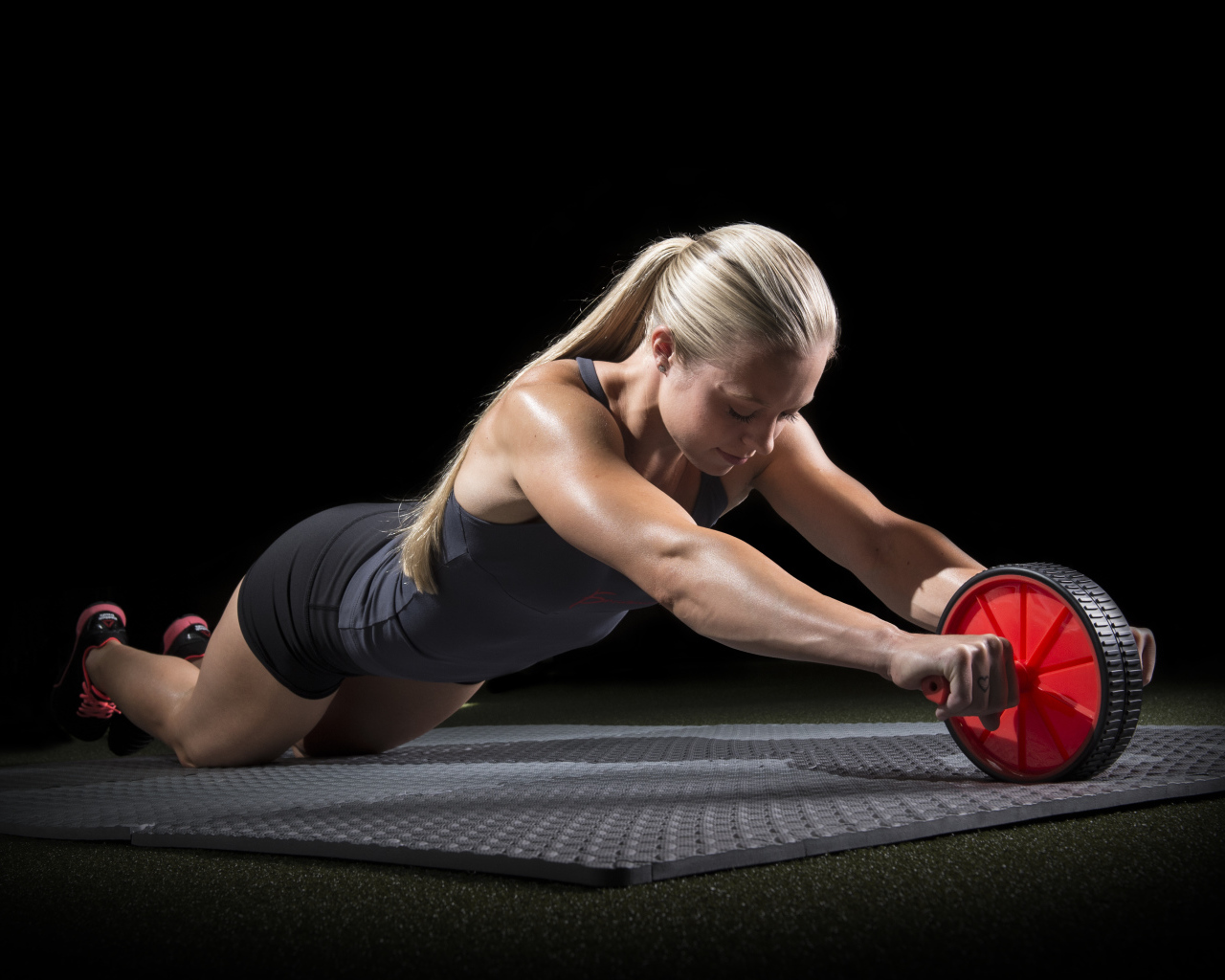 Девушка занимается фитнесом с колесом