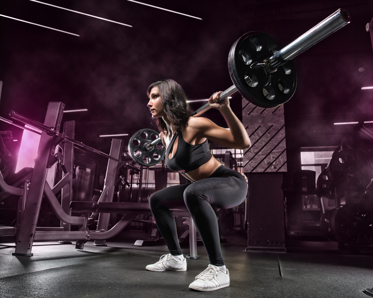 Девушка тяжелоатлет поднимает штангу в спортзале