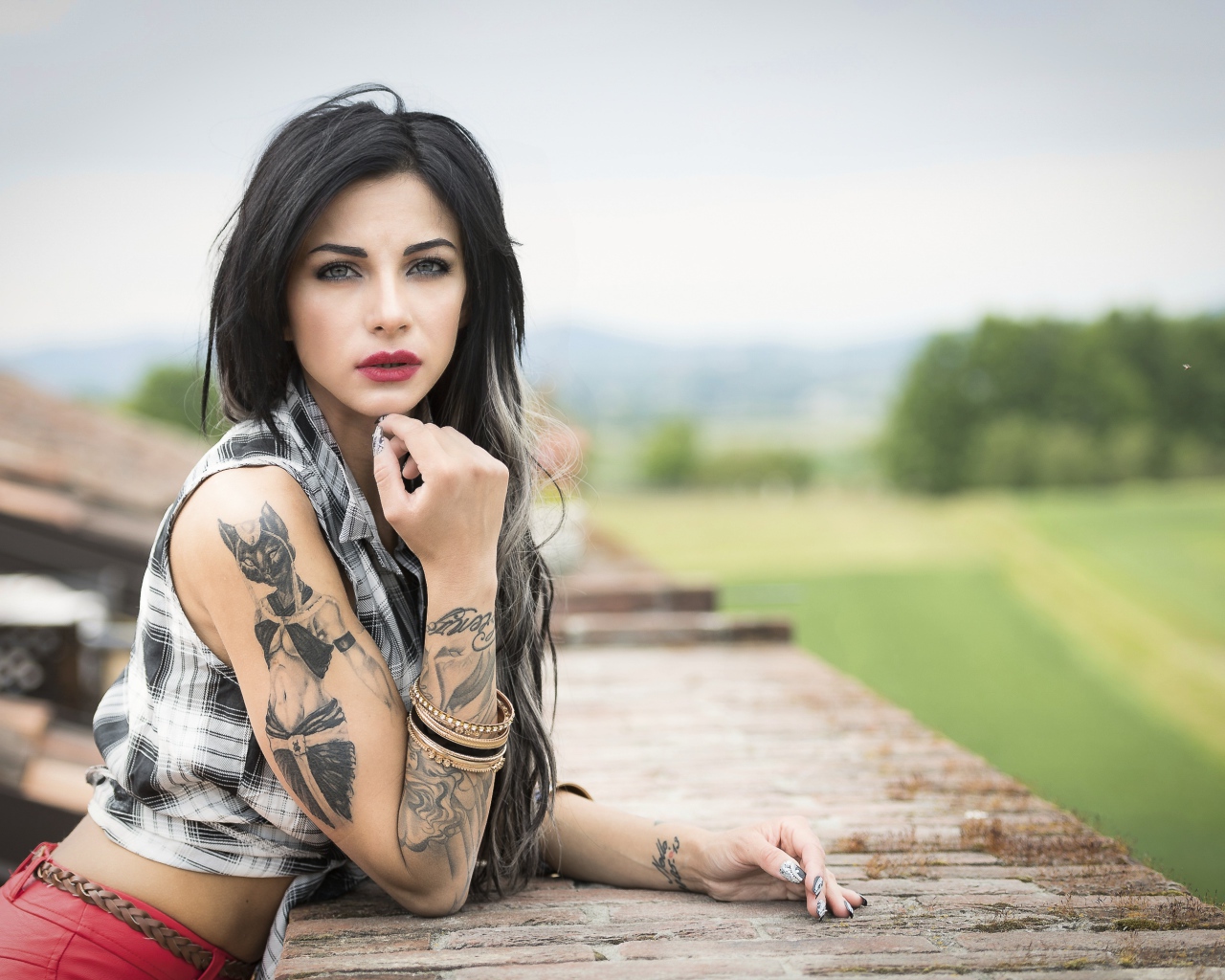 Молодая девушка брюнетка с татуировками на руках
