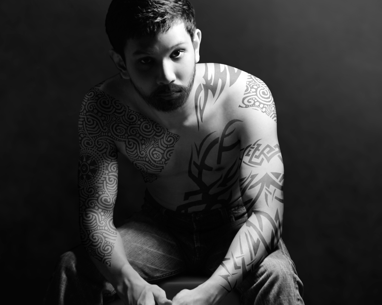 Молодой парень с татуировками на теле на сером фоне