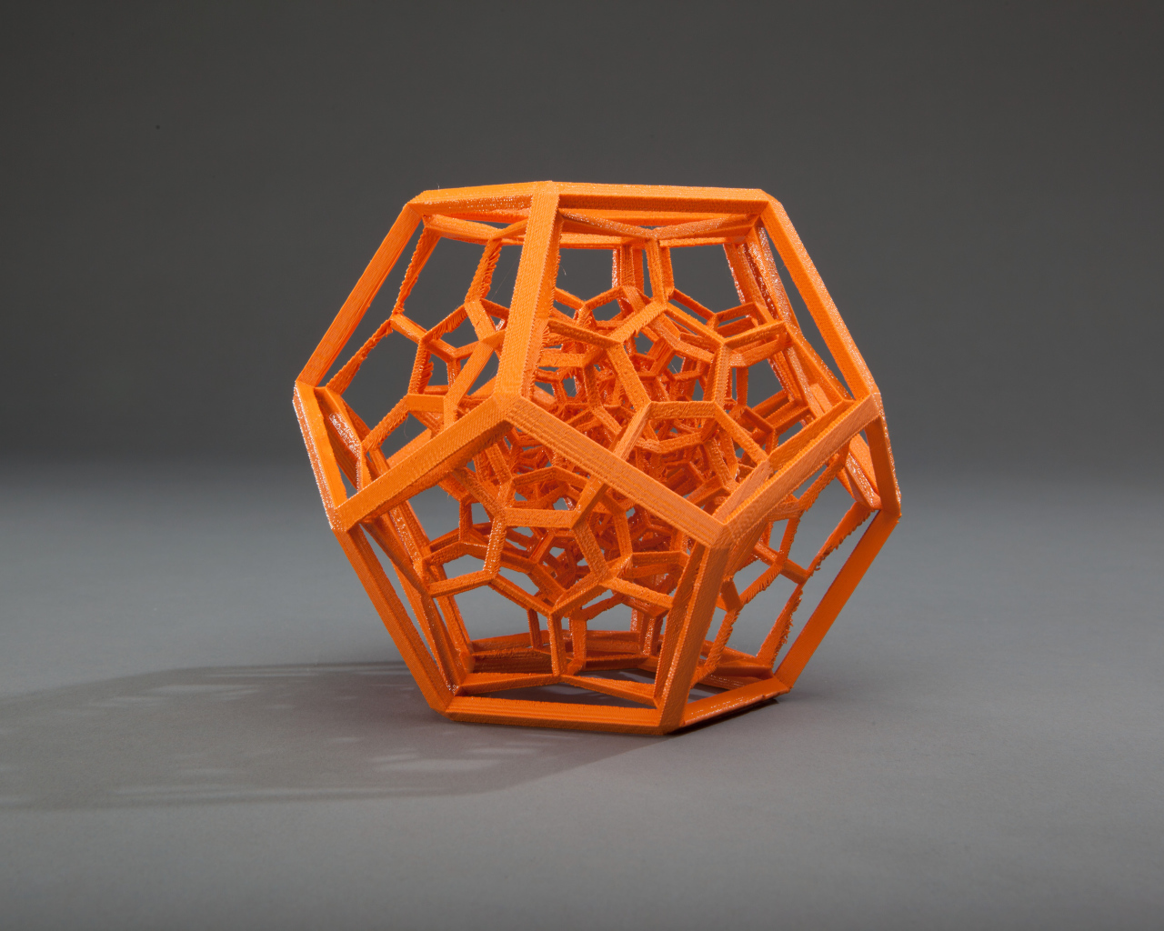 Оранжевый многогранник на сером фоне 3д