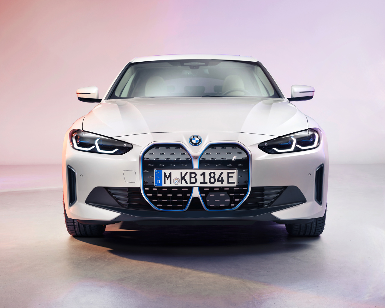 Автомобиль BMW I4 2021 года вид спереди на розовом фоне