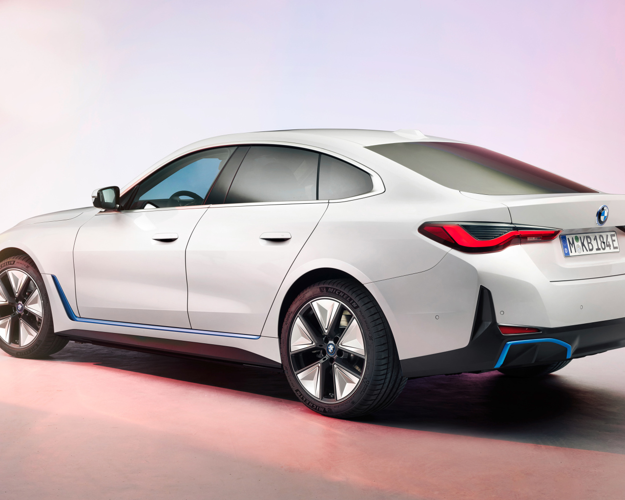 Белый автомобиль BMW I4 2021 года на розовом фоне