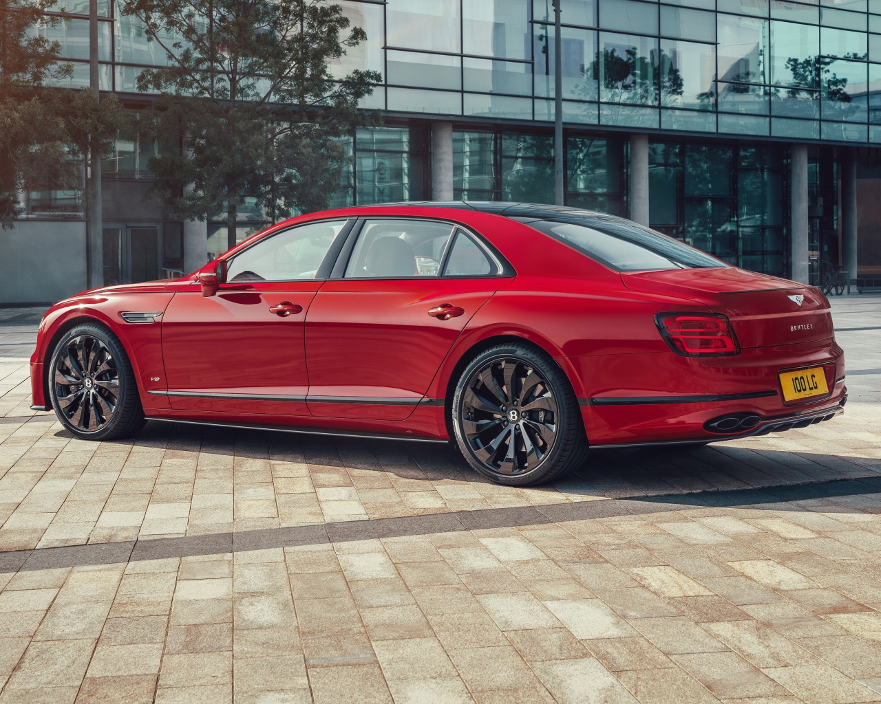 Красный автомобиль Bentley Flying Spur V8 2020 года у здания 