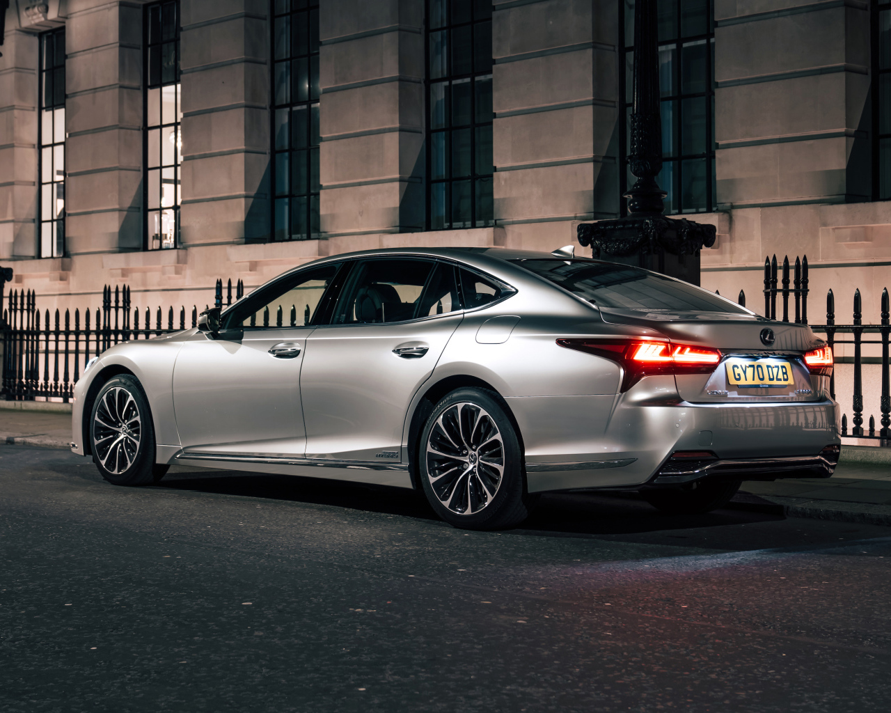 Серебристый автомобиль Lexus LS 500h 2021  года вид сзади