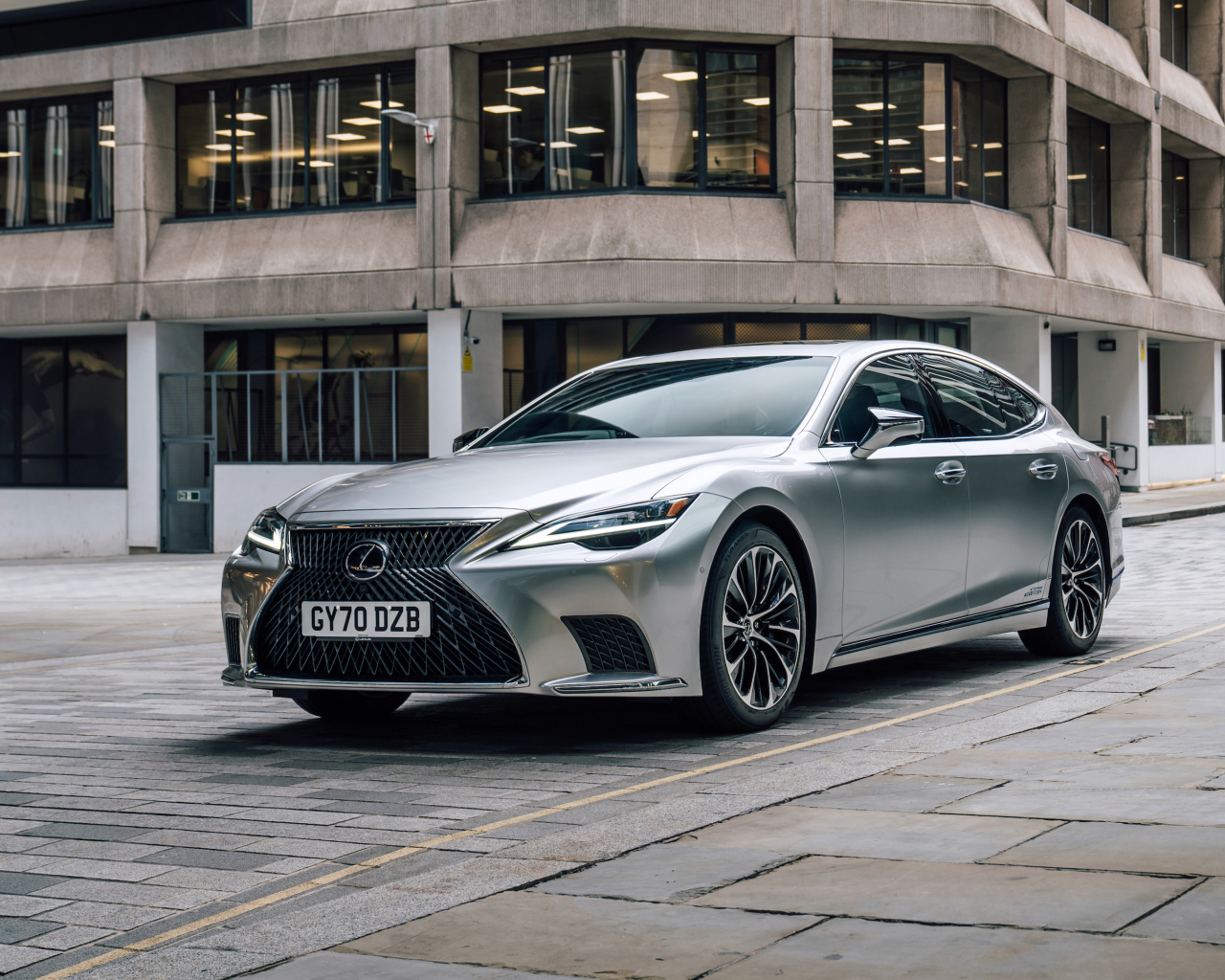 Серебристый автомобиль Lexus LS 500h 2021 года в городе у дома