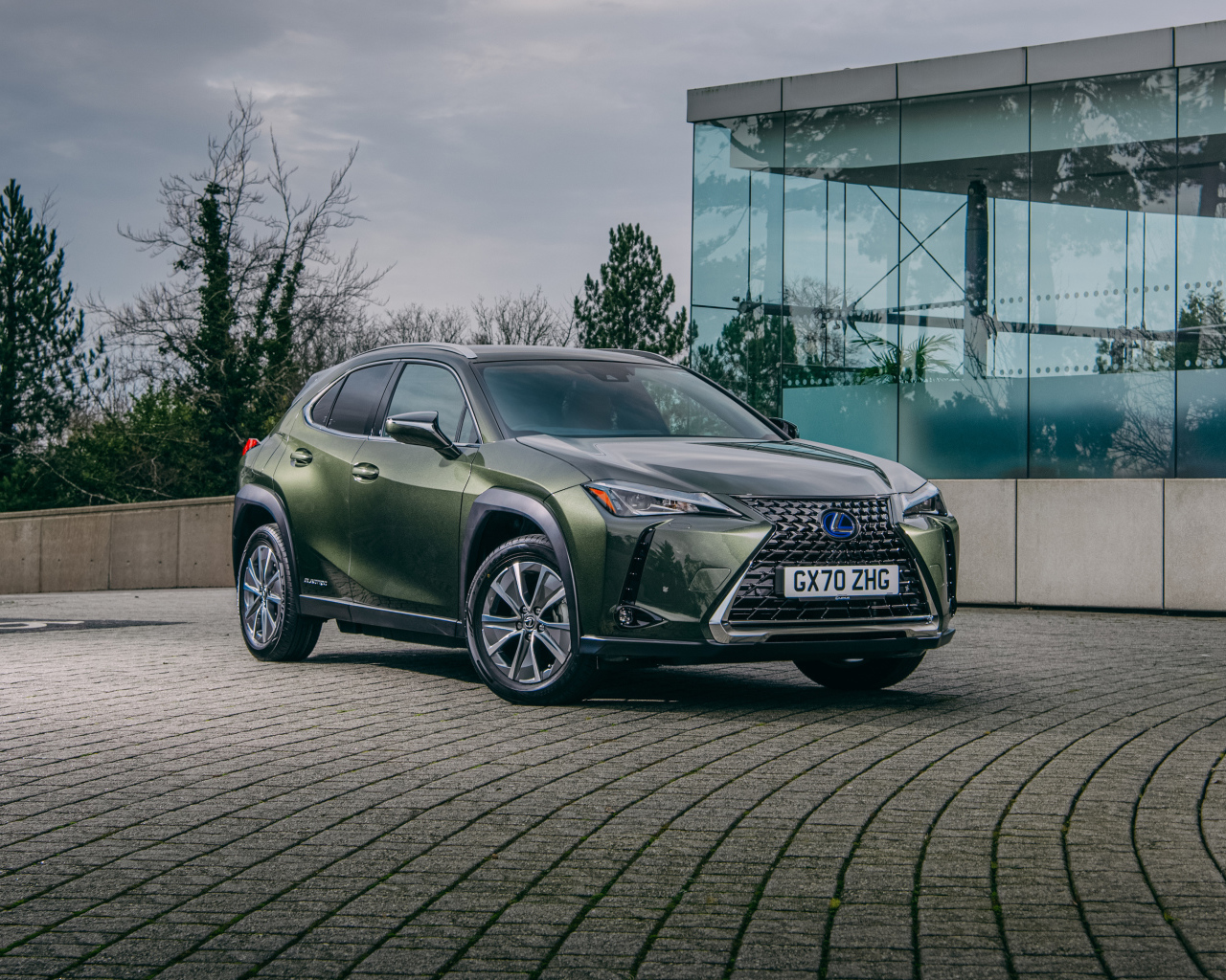 Зеленый автомобиль Lexus UX 300e 2021 года у стеклянной стены