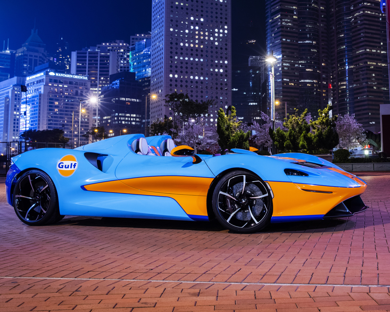 Автомобиль McLaren Elva Gulf Theme, 2021 года на фоне города