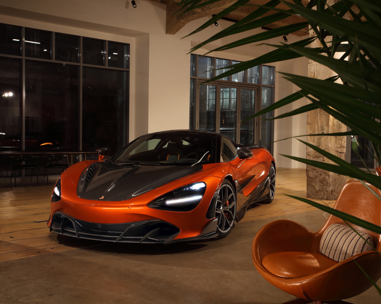 Оранжевый автомобиль  McLaren 720S у дома с креслом