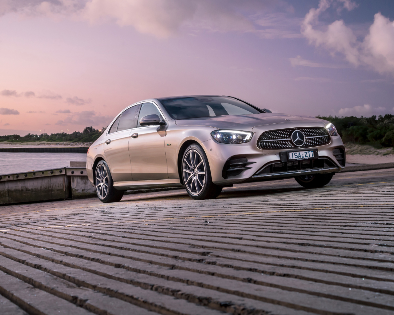 Серебристый автомобиль Mercedes-Benz E 300 E AMG Line 2021 года у реки