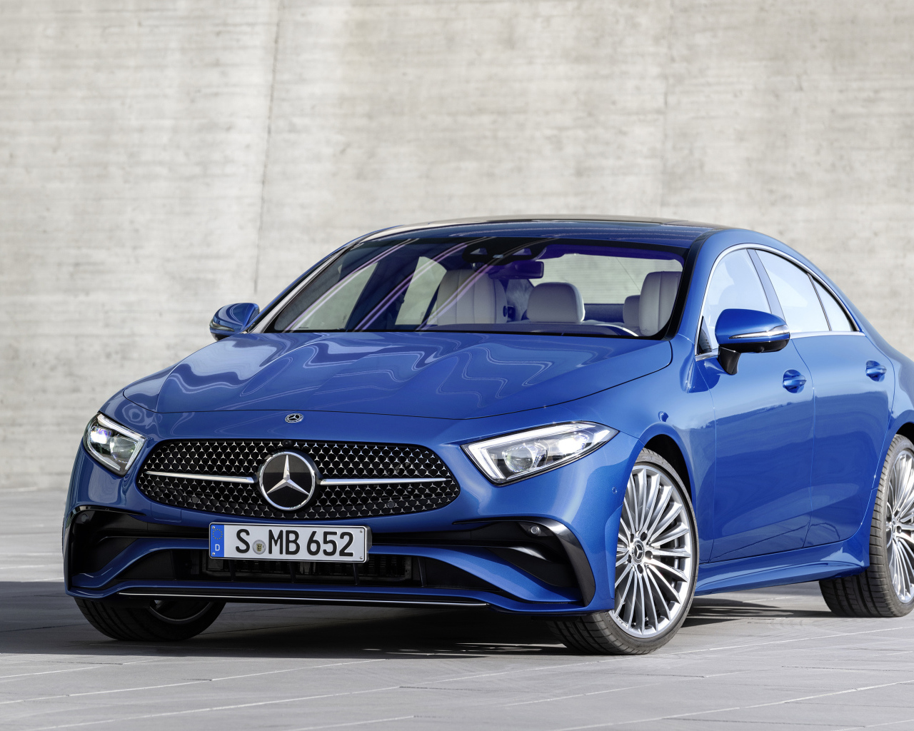 Синий автомобиль Mercedes-Benz CLS 350 AMG Line 2021 года на фоне серой стены