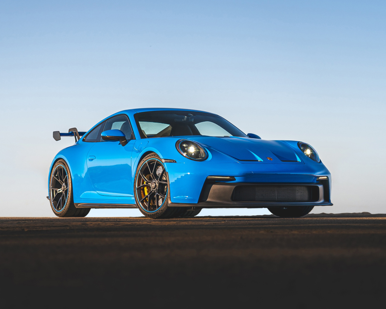 Синий автомобиль Porsche 911 GT3 2021 года на фоне неба