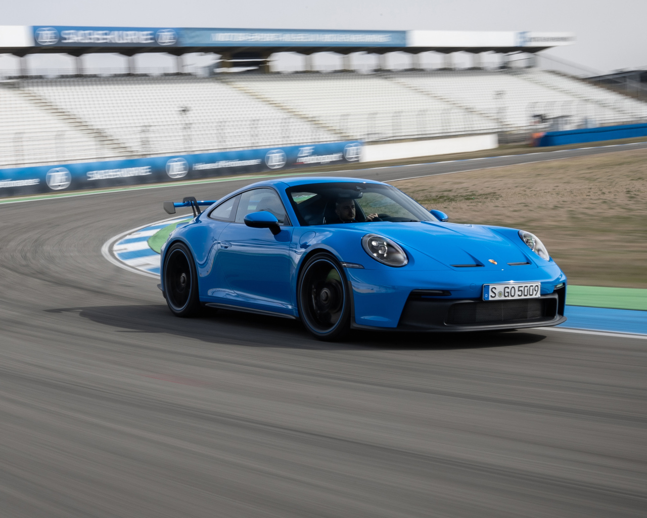 Голубой автомобиль Porsche 911 GT3 2021 года на стадионе