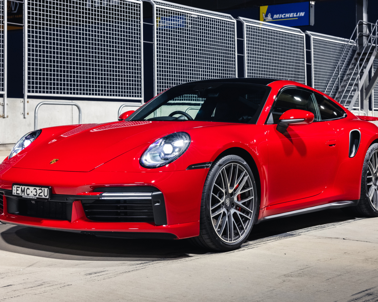 Красный автомобиль Porsche 911 Turbo 2021 года на стадионе