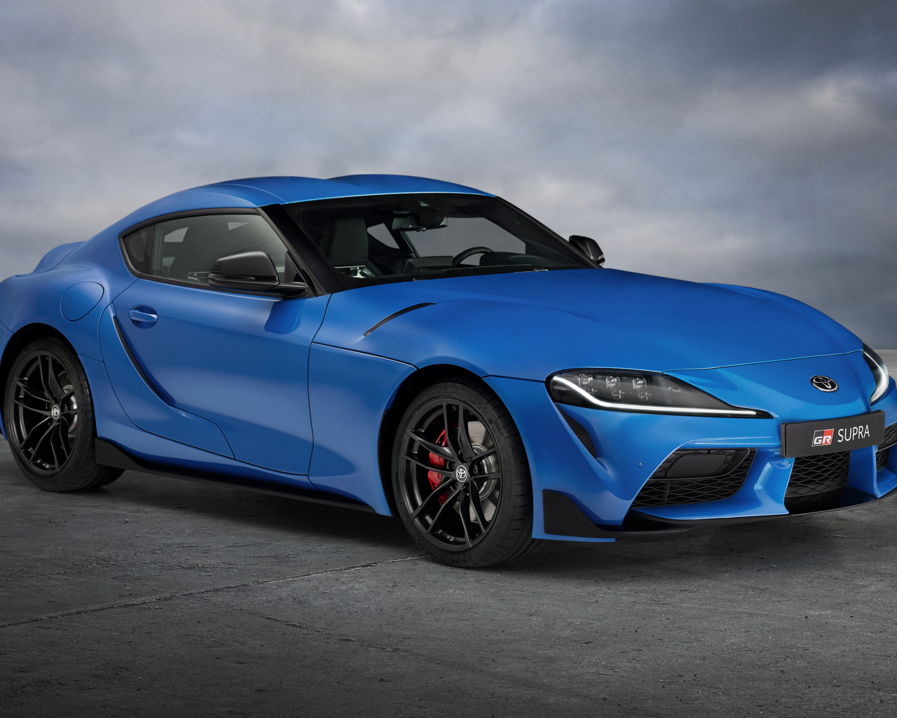 Синий автомобиль Toyota GR Supra, 2021 года на сером фоне