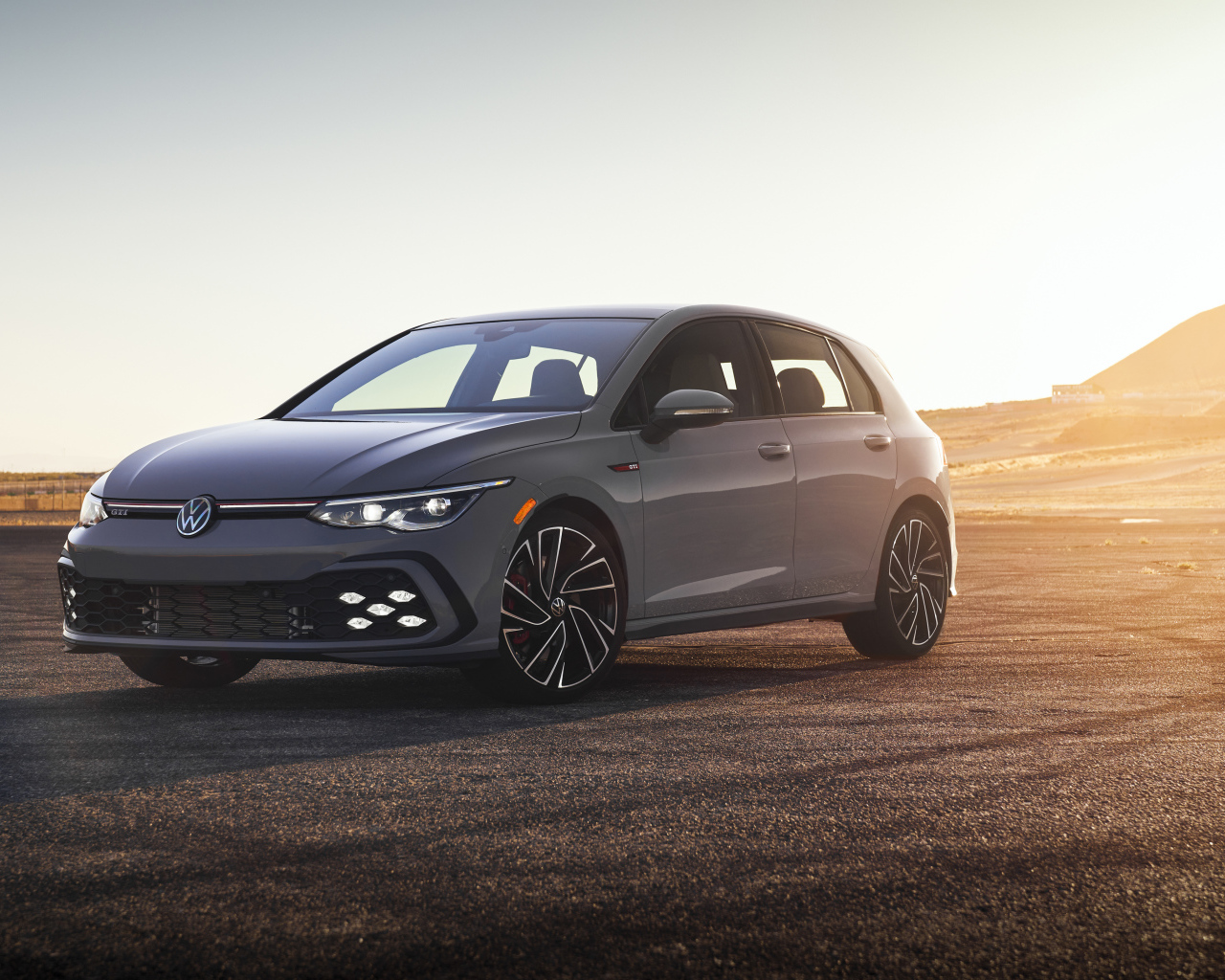 Серебристый автомобиль Volkswagen Golf GTI на фоне заката