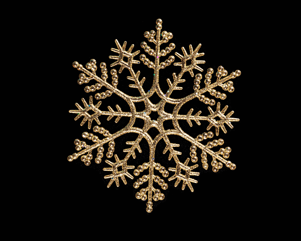 Красивая золотистая снежинка на черном фоне