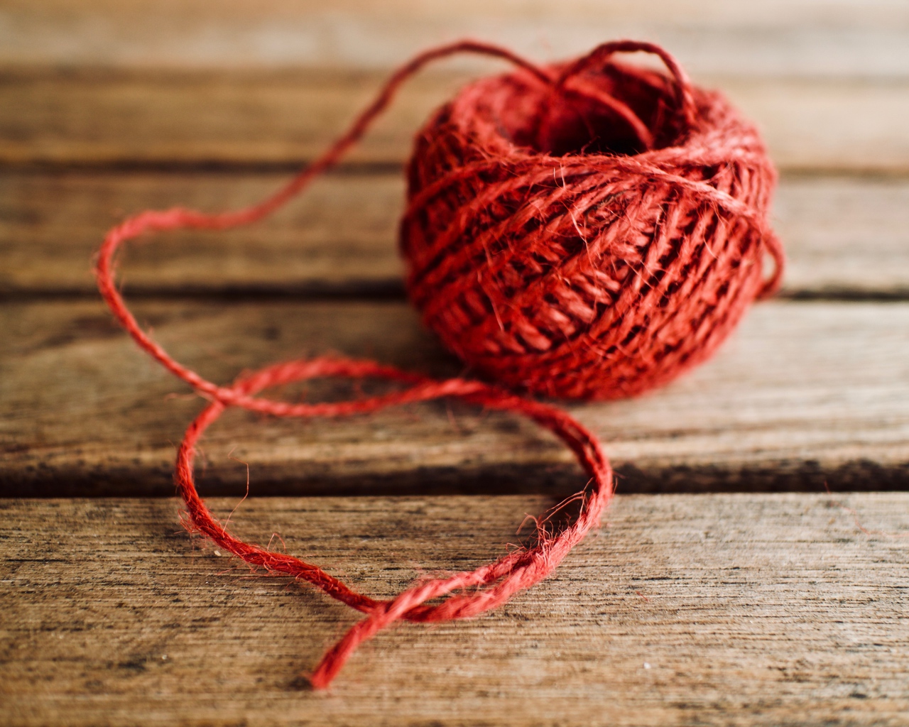 Клубок красной пряжи на деревянном столе 