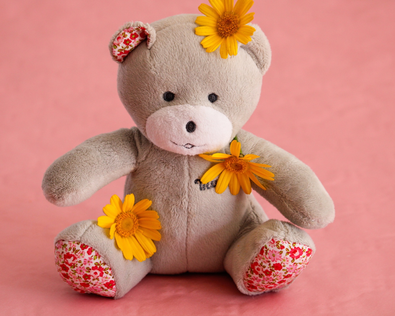 Красивый плюшевый мишка с цветами на розовом фоне