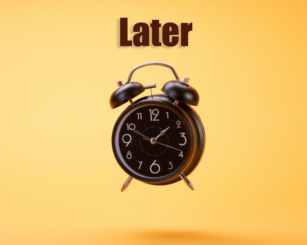 Большой черный будильник на желтом фоне 