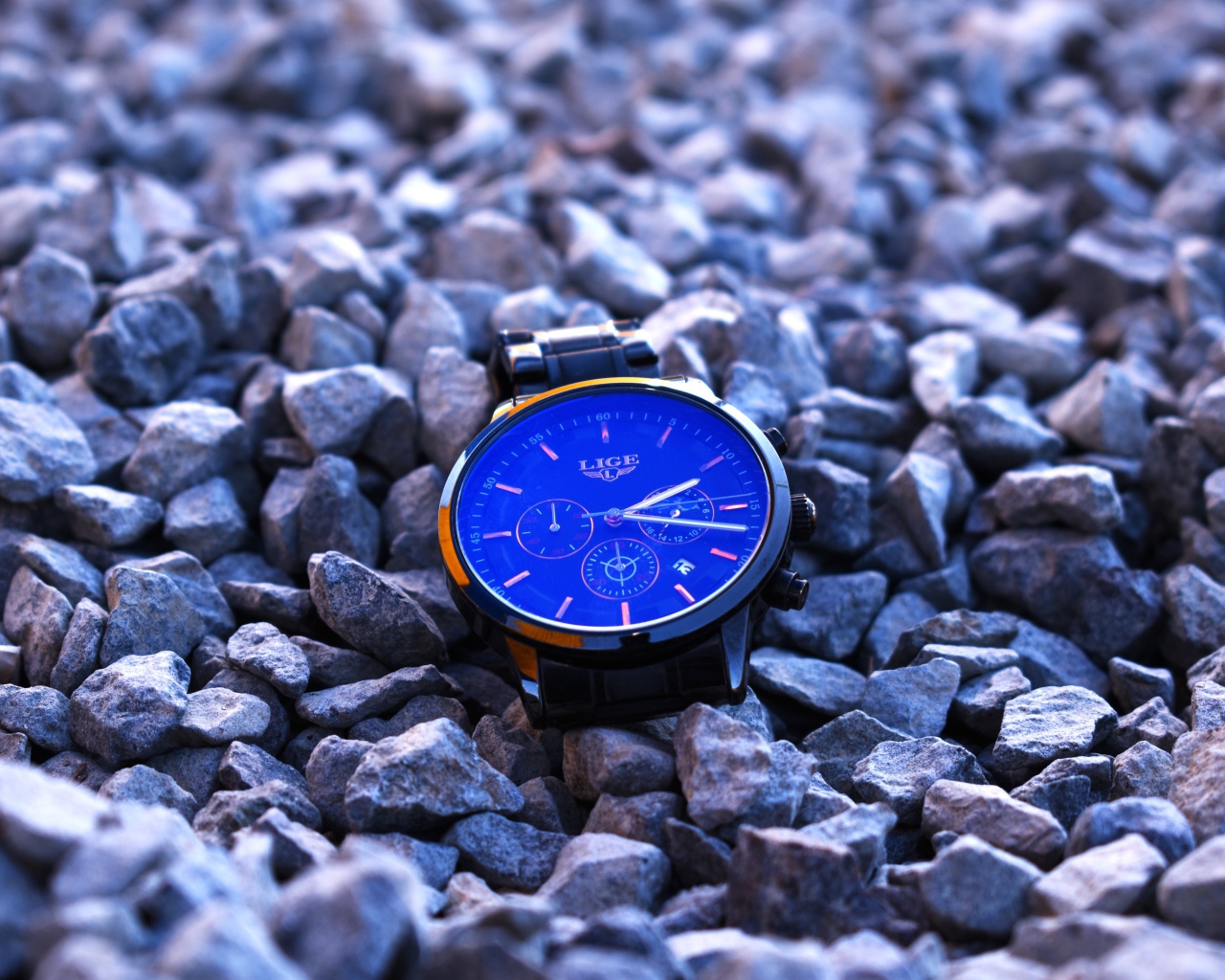 Голубые наручные часы лежат на камнях