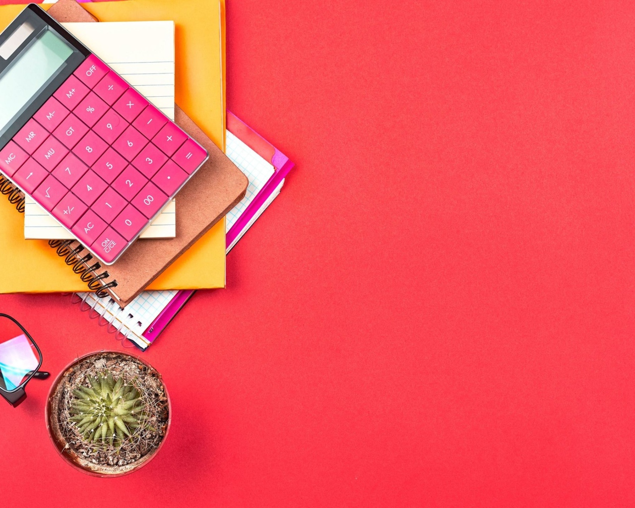 Калькулятор с очками и блокнотами на розовом фоне 