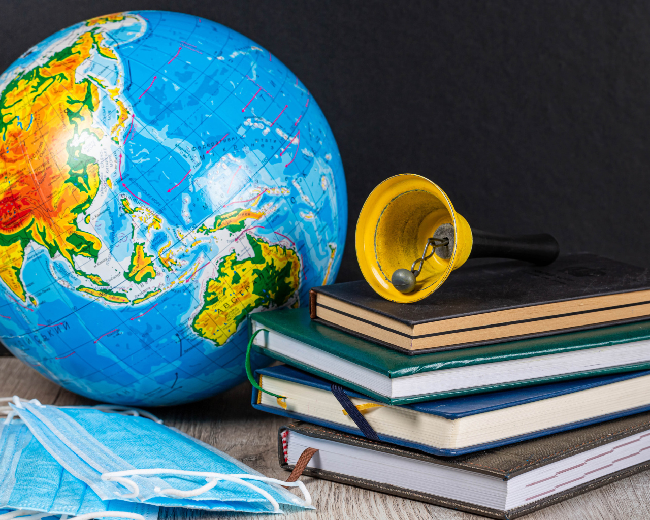 Глобус, книги, колокольчик и медицинские маски 